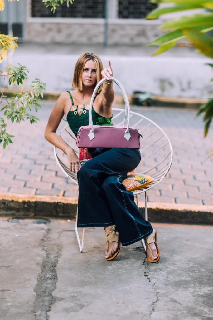 Model seated with the Kuma purple leather shoulder bag