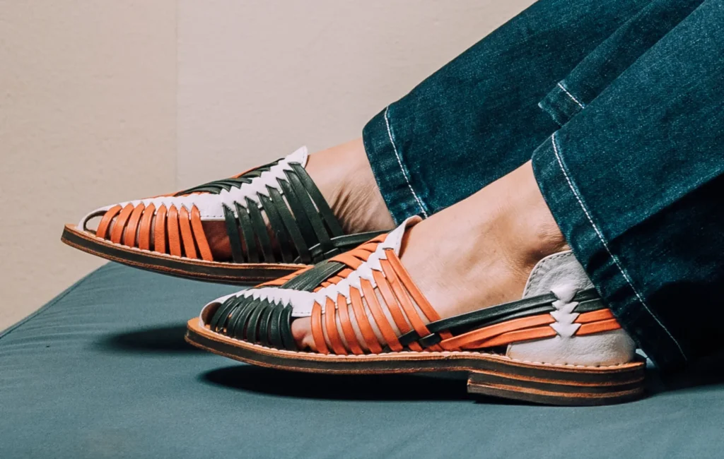 Woman wearing Yuma woven leather espadrilles with cropped denim, seated on a teal cushion